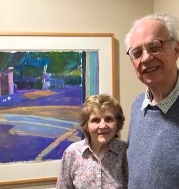 Frank and his wife Margaret, both former museum directors, stand by a painting in an art exhibit curated the Frank and Kendal Art Display Committee.