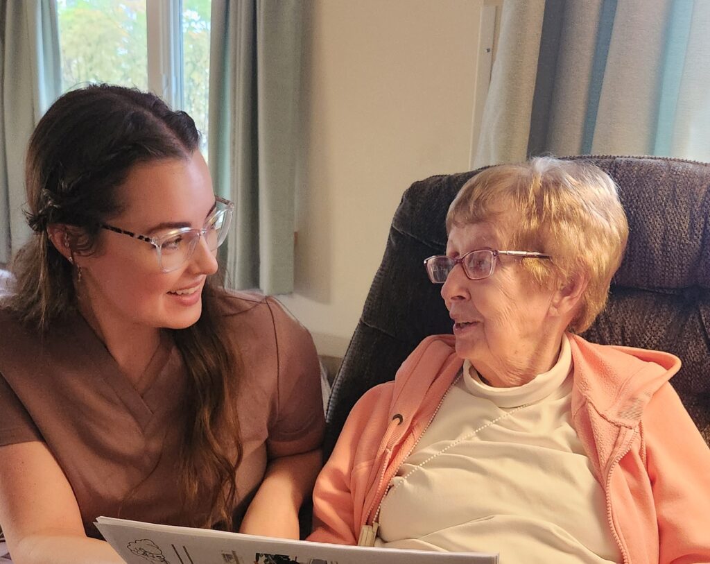 Kendal at Ithaca caregiver, Kieren Hoey, reads with resident Ann Barron.